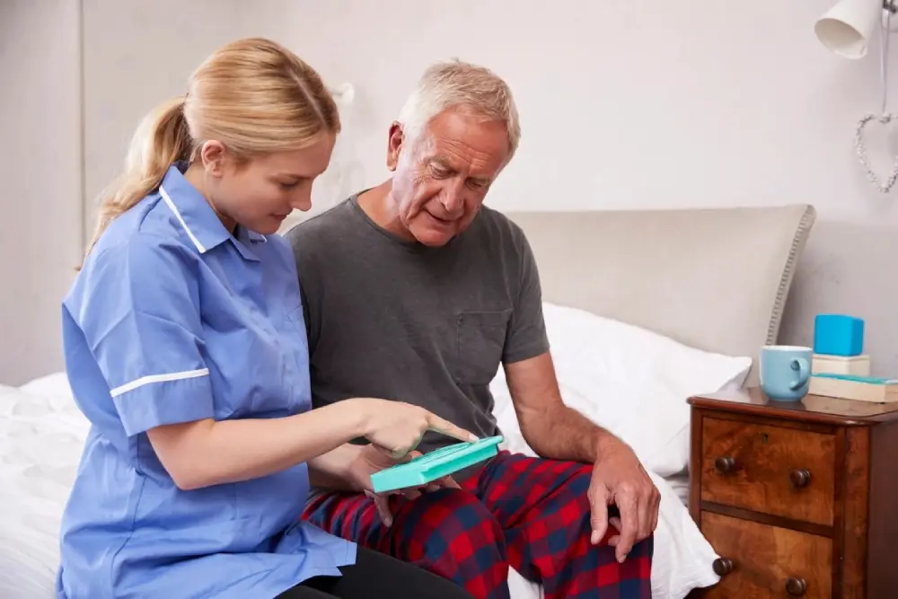 A nurse and an older man looking at something on the table.